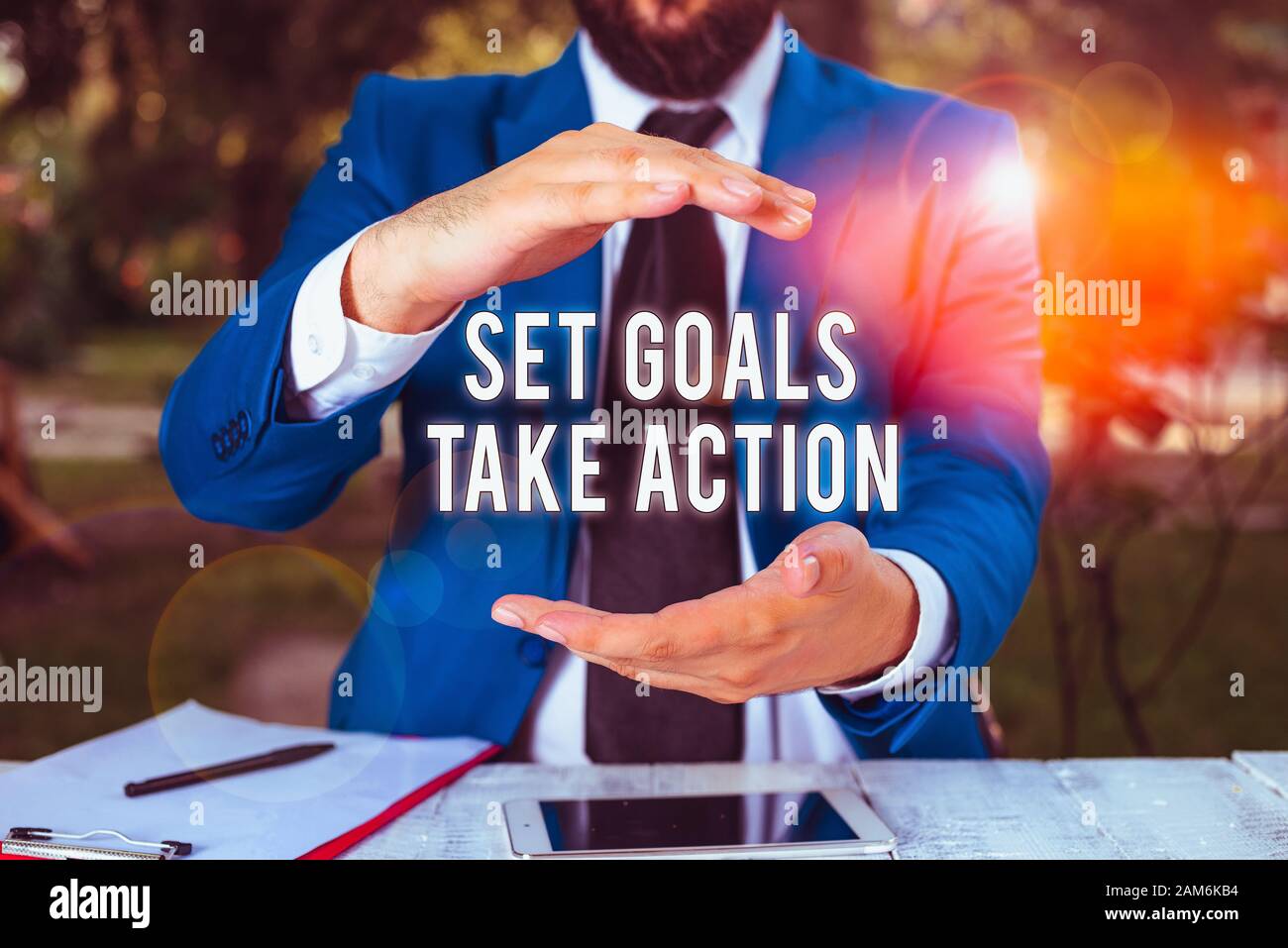 Conceptual hand writing showing Set Goals Take Action. Concept meaning Act on a specific and clearly laid out plans Man in front of table. Mobile phon Stock Photo