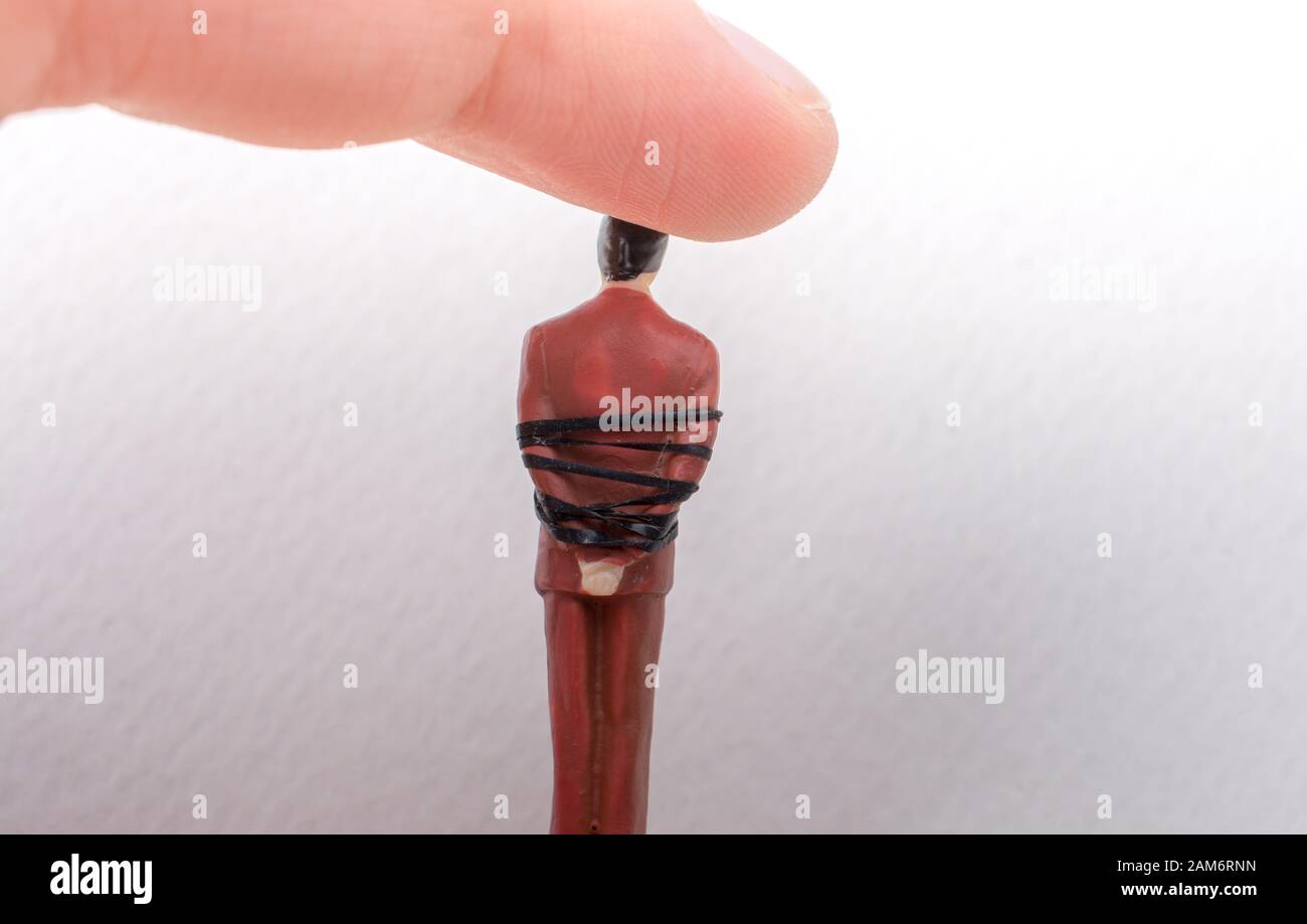 Hand holding tiny figurine of man model tied in a rope Stock Photo - Alamy