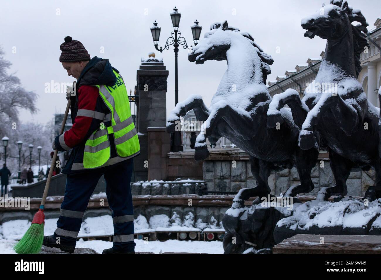 Moscow, Russia. 11st of January, 2020  An employee of communal services removes snow near the sculptural composition 'Four seasons' on Manezh square in central Moscow, Russia Stock Photo