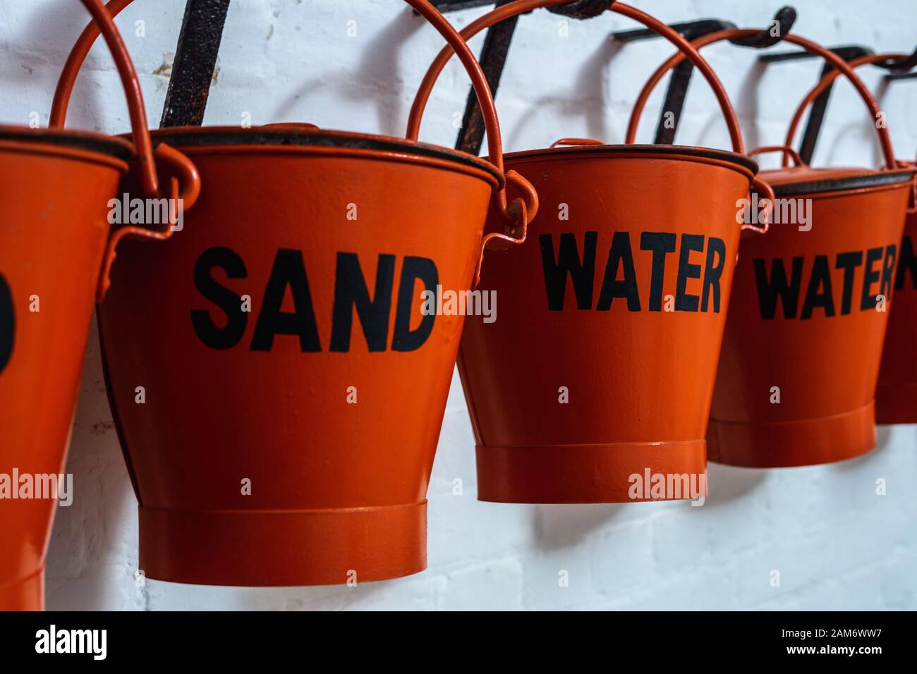 buckets filled with sand and water hanging on the wall for a fire emergency to aid firefighting Stock Photo