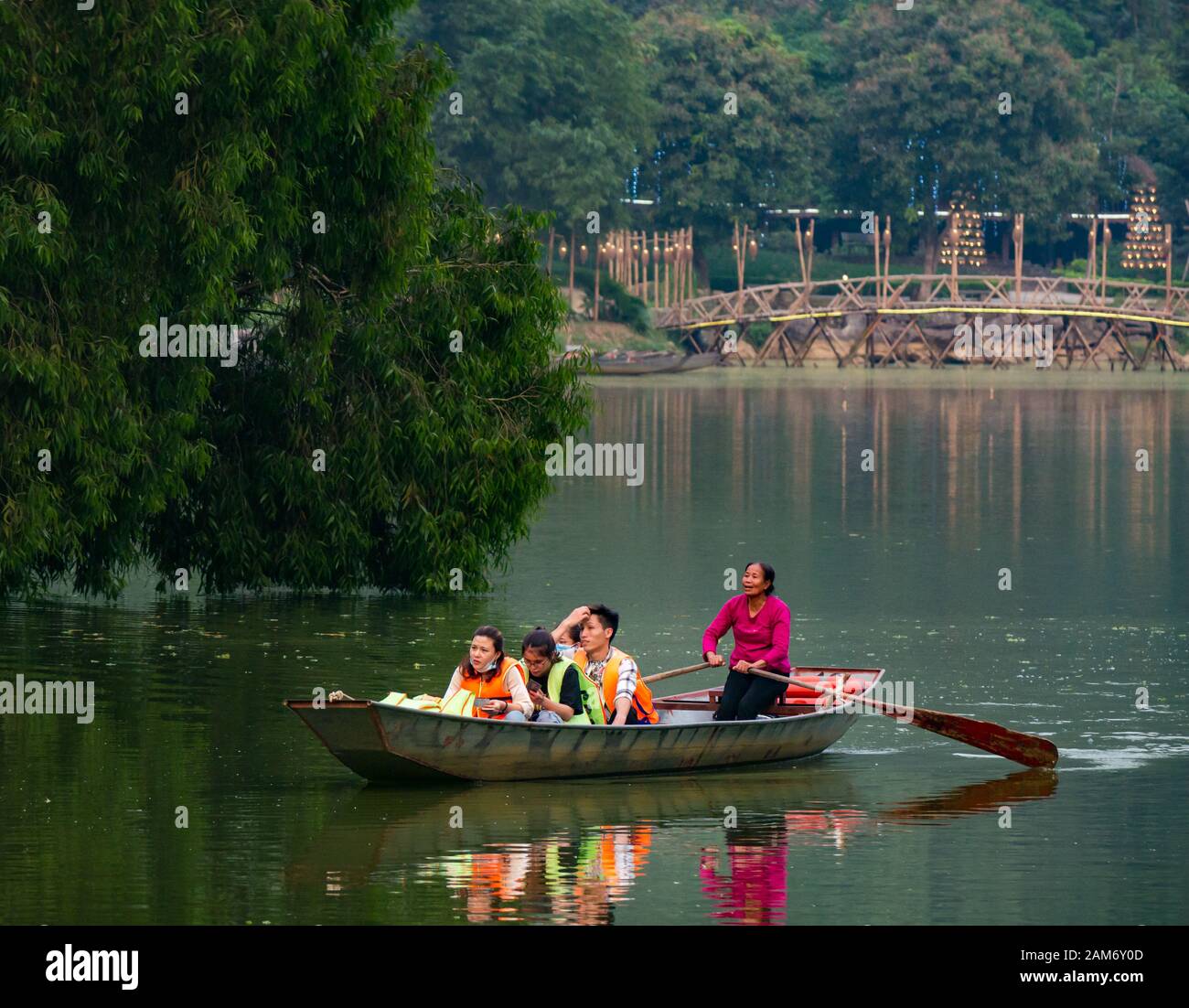 Local woman rowing group of Asian tourists in sampan, Thung Nham Bird Park, Tam Coc, Ninh Binh, Vietnam, Asia Stock Photo