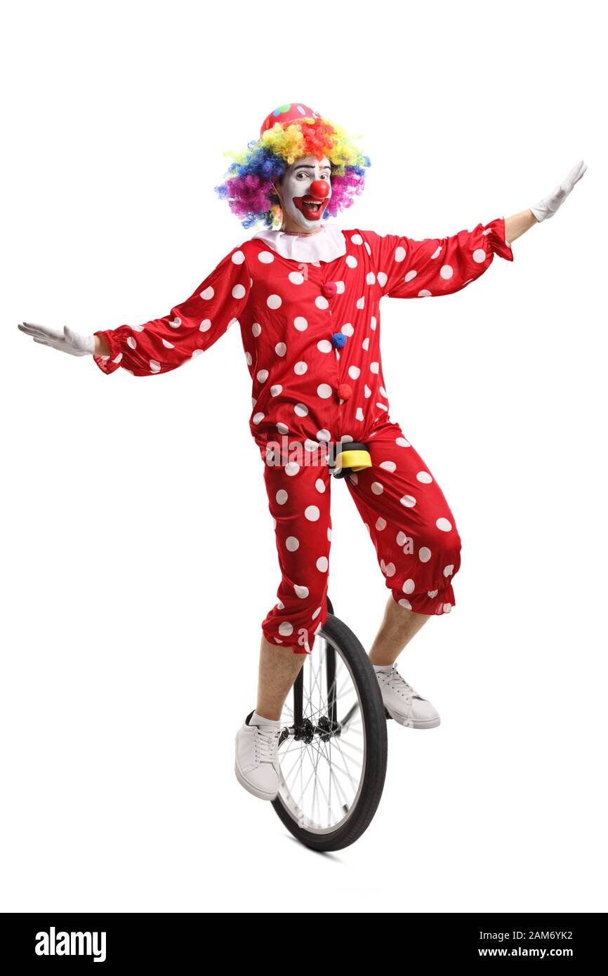 Clown in a red polka dot costume riding a unicycle isolated on white background Stock Photo