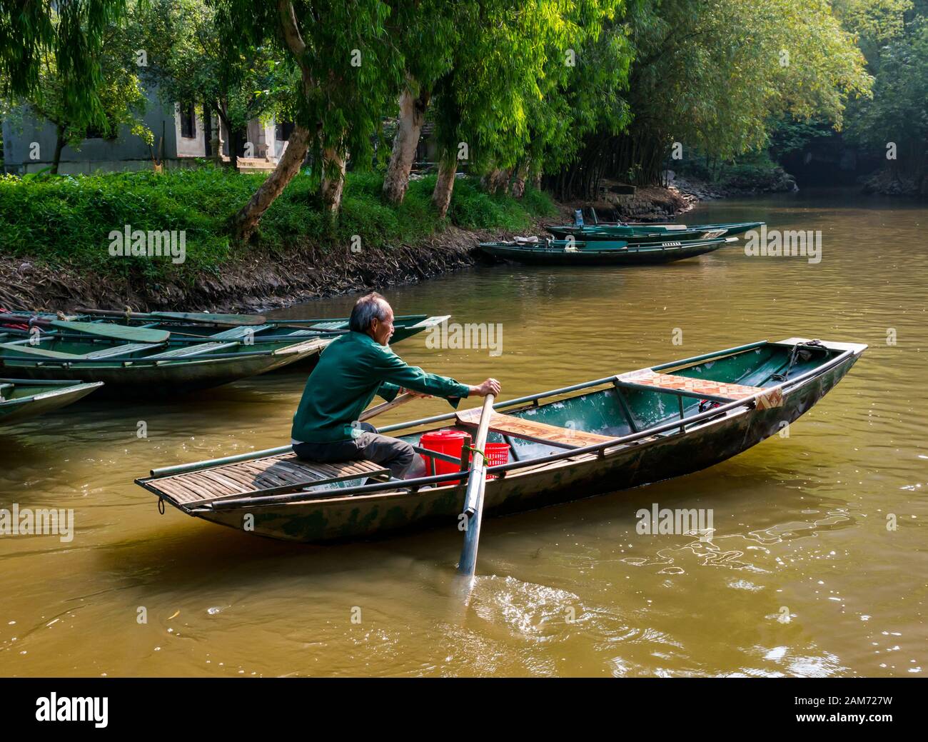 Older local Asian man with grey beard rowing sampan, Tam Coc, Ninh Binh, Vietnam, Asia Stock Photo