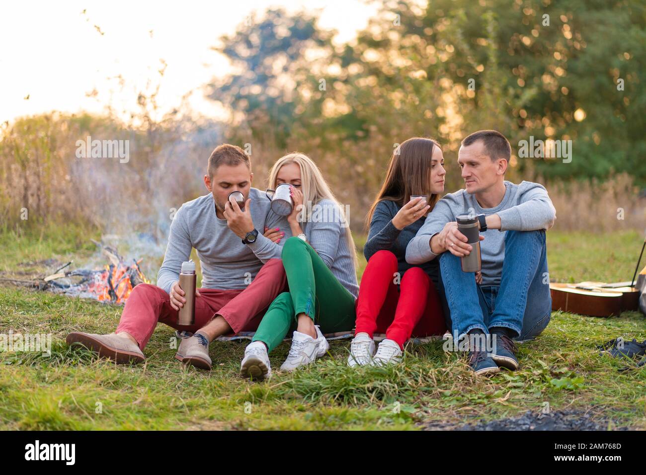 A Group Of Friends Is Enjoying A Warming Drink From A Thermos On A Cool Evening By A Fire In The Forest Fun Time Camping With Friends Stock Photo Alamy