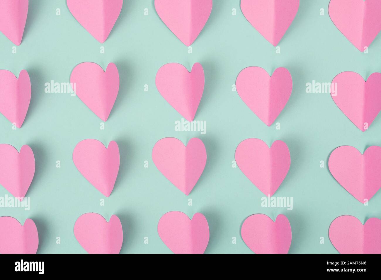 Seamless background made of pink paper hearts on mint color background. Top view Stock Photo