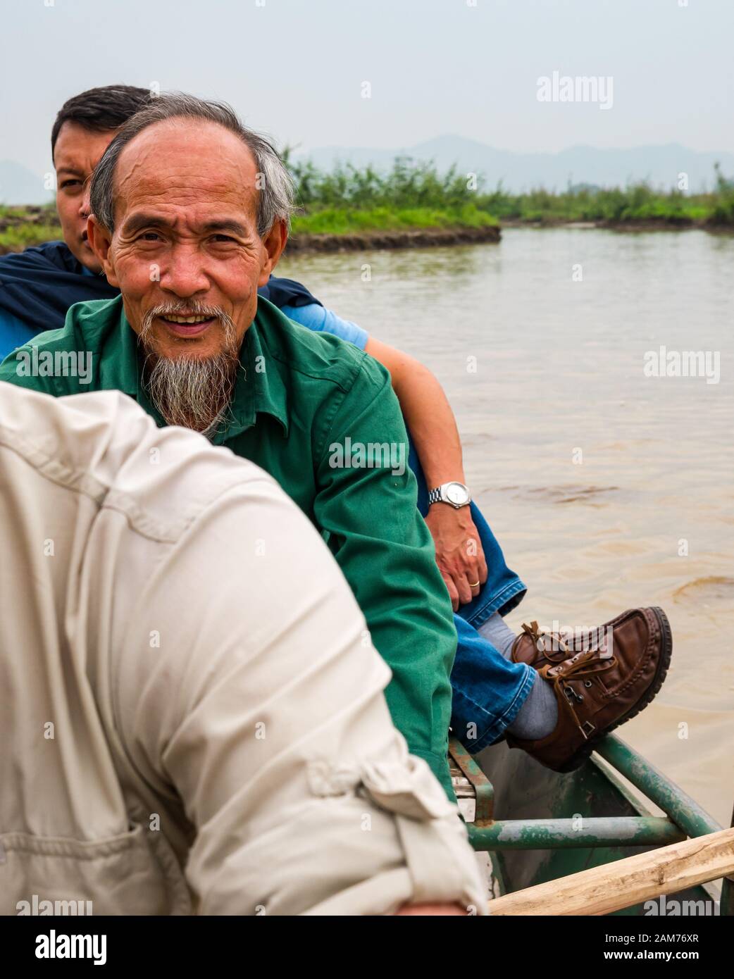 Old local Asian man with beard rowing sampan on river, Tam Coc, Ninh Binh, Vietnam, Asia Stock Photo