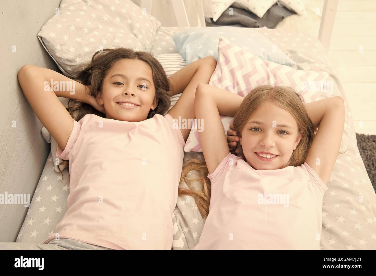 Being as happy as the day is long. Happy little girls having afternoon nap in bedroom. Adorable small children relaxing on bed. Enjoying happy childhood. Carefree and happy. Stock Photo