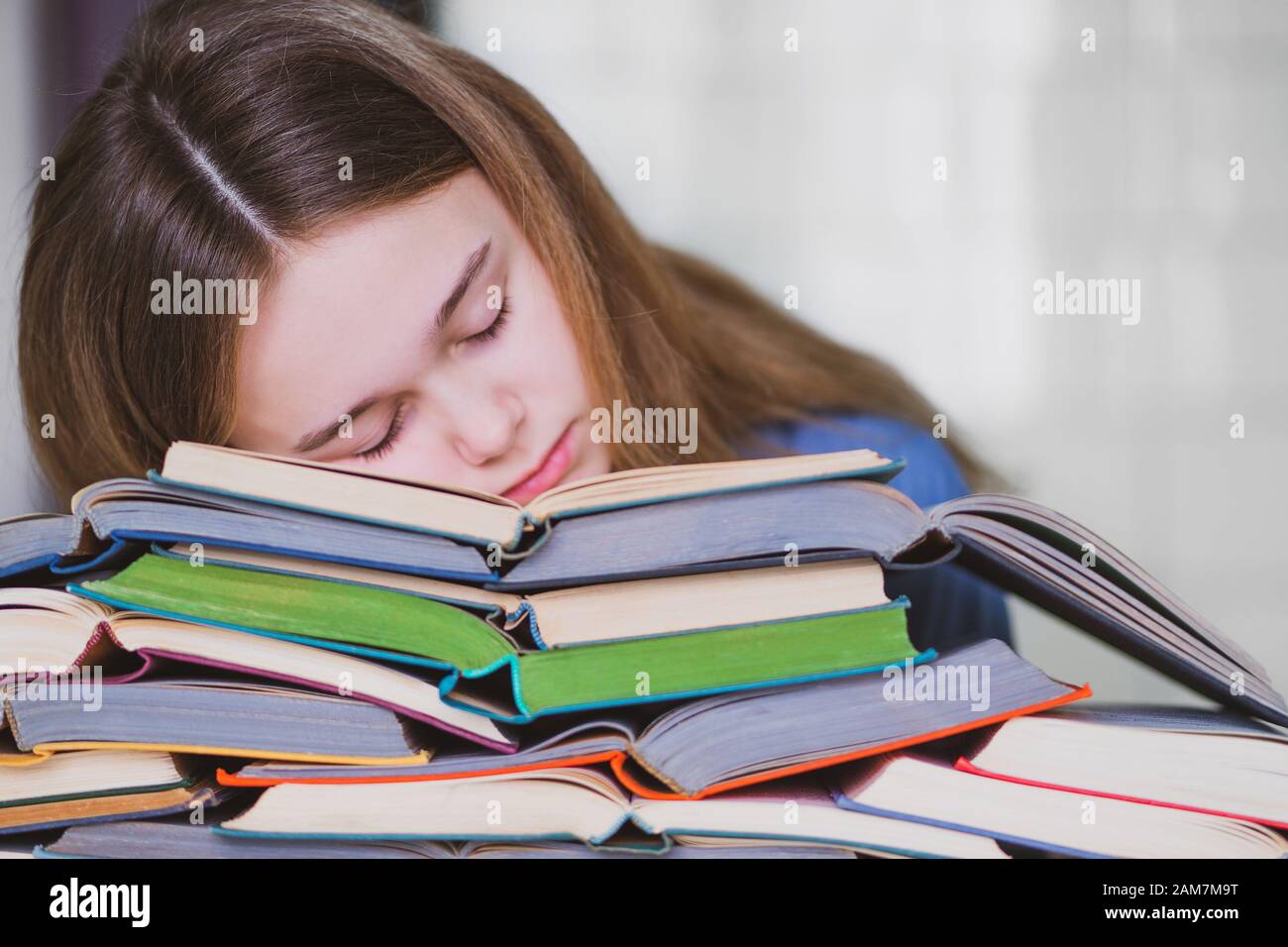 Stressed college student tired of hard learning with books in exams tests preparation, overwhelmed high school teen girl exhausted with difficult studies or too much homework, cram concept Stock Photo