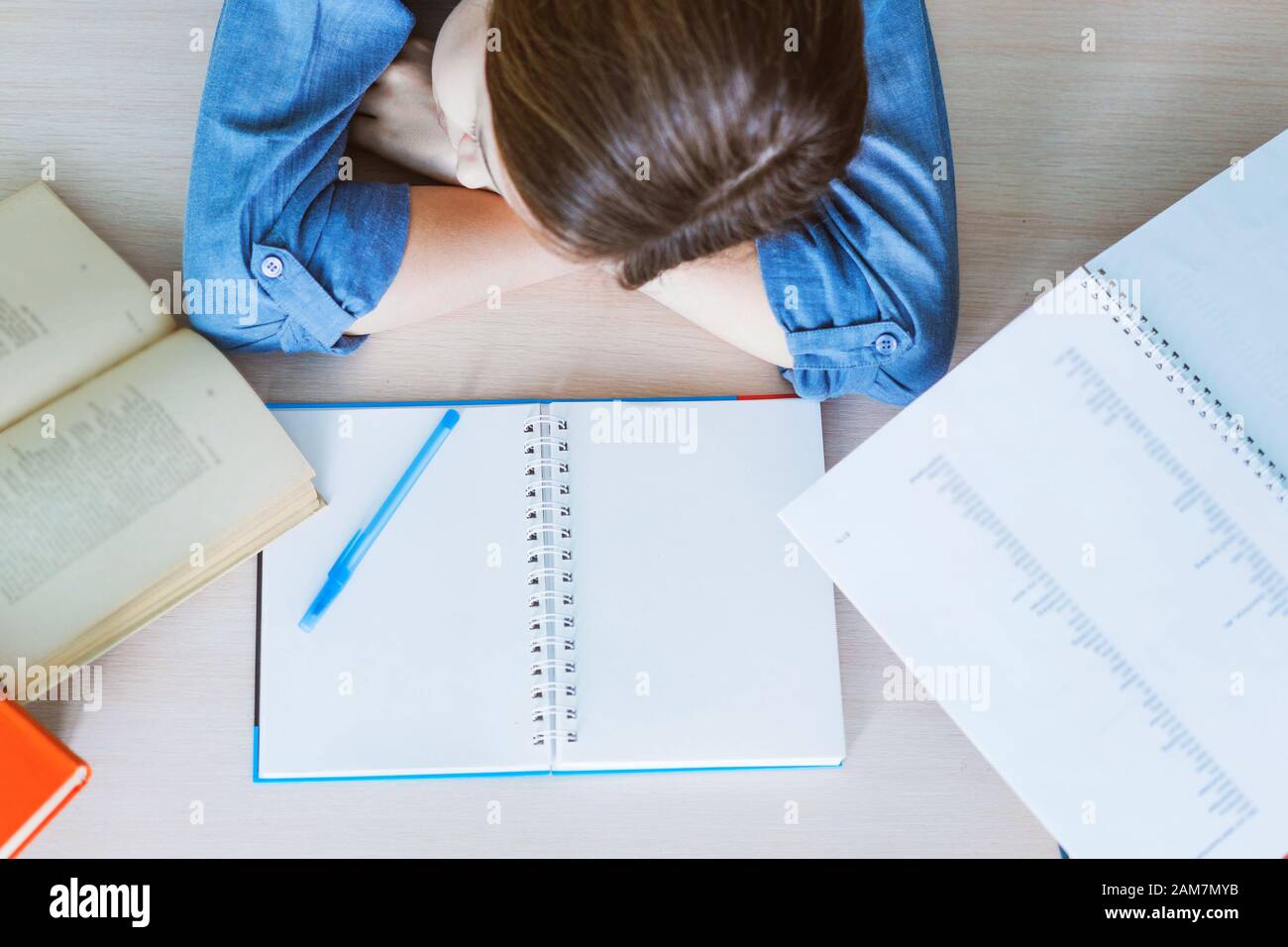 Stressed college student tired of hard learning with books in exams tests preparation, overwhelmed high school teen girl exhausted with difficult studies or too much homework, cram concept Stock Photo