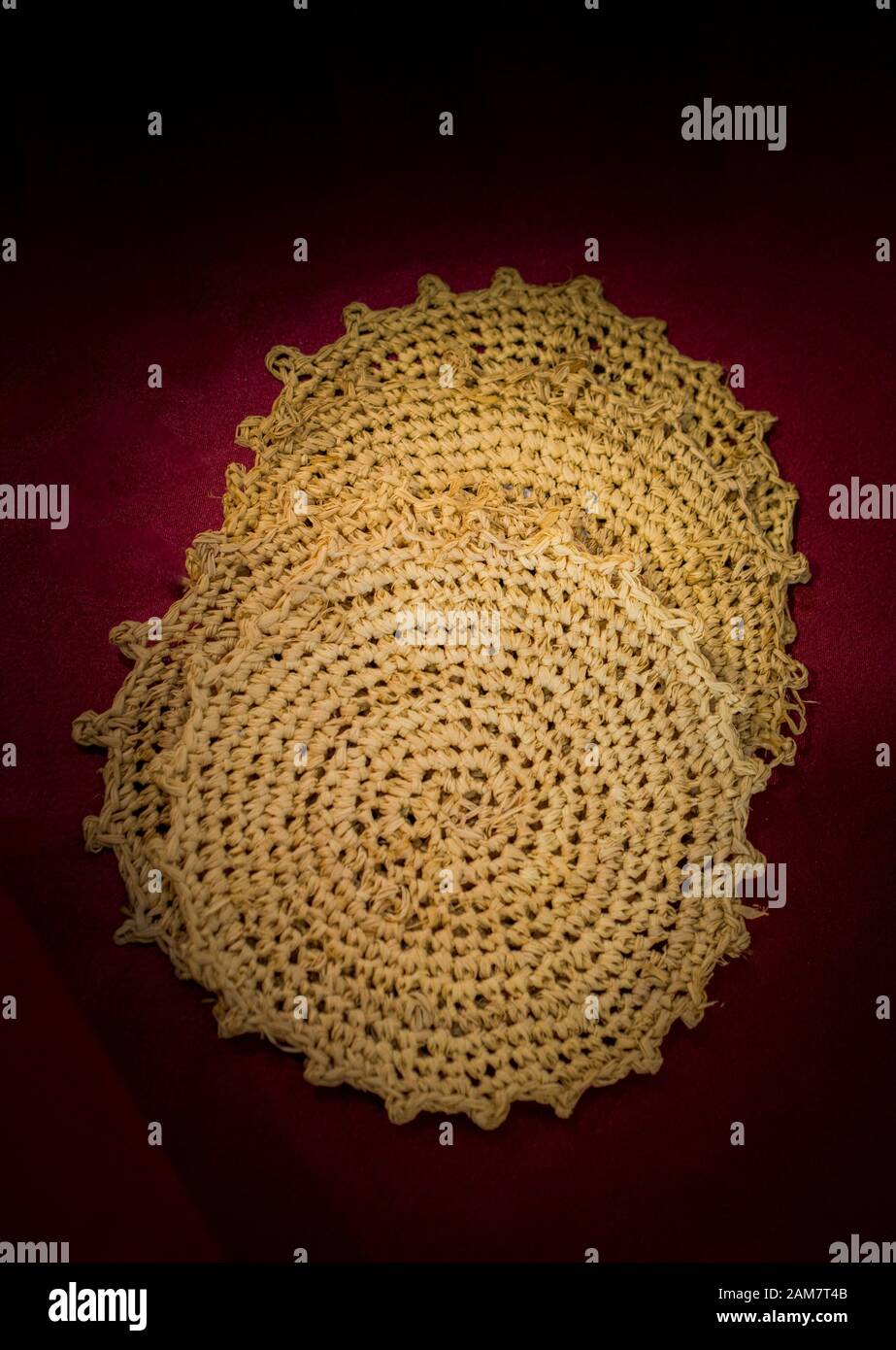 Four straw trivets on a red background on display Stock Photo - Alamy