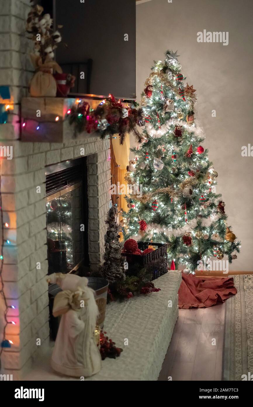 Lit and decorated Christmas tree, fireplace mantle and hearth indoors. Stock Photo