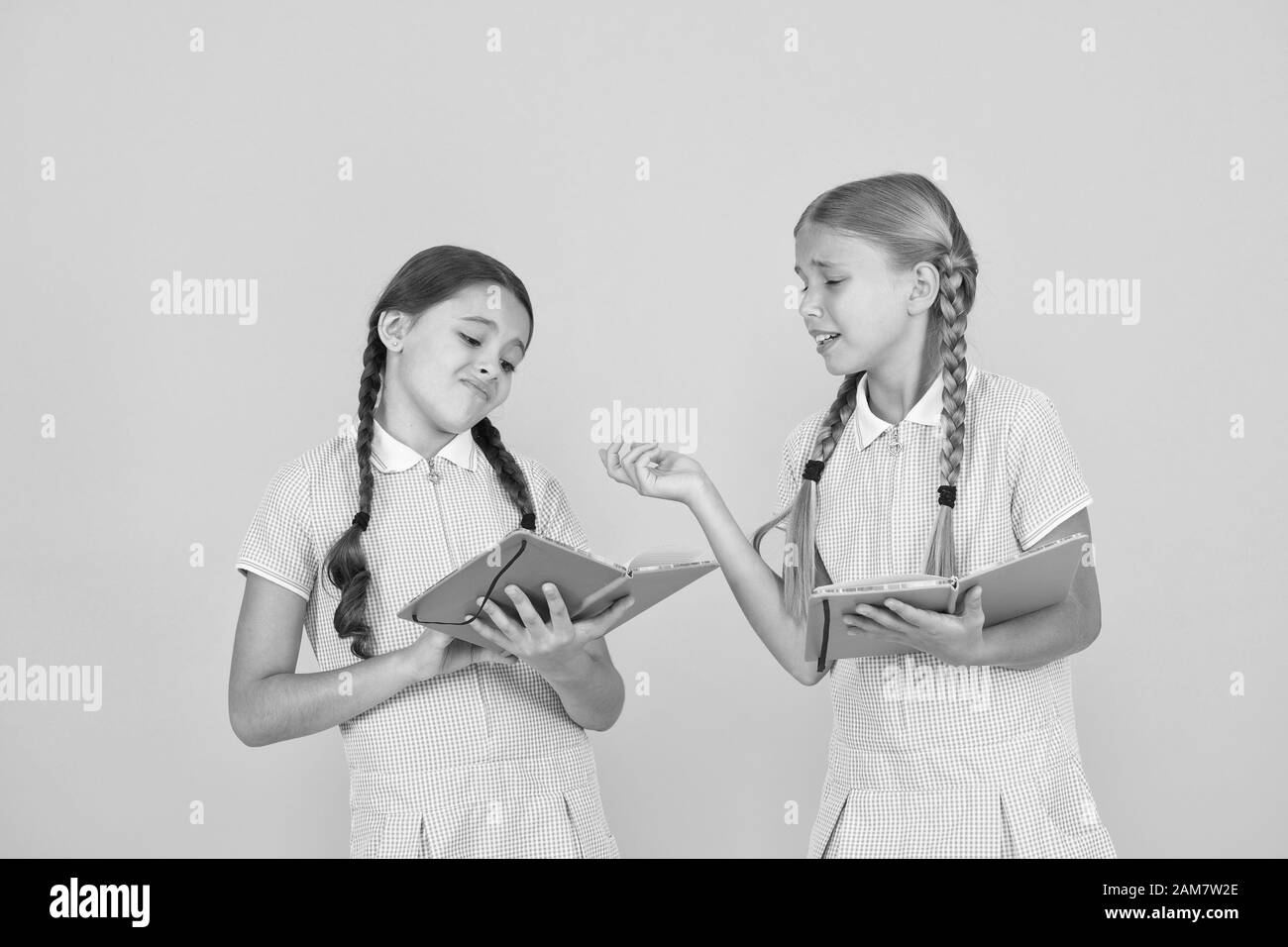 Reading books. Reading and retelling. Small children holding books yellow background. Sincere interest. Little girls with encyclopedia or childrens books. School library. Educational books for school. Stock Photo