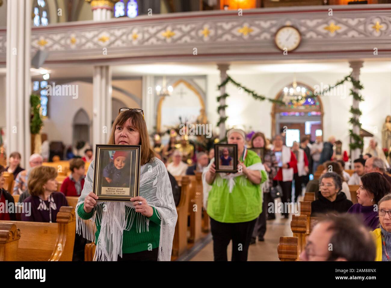 Detroit, Michigan, USA. 11th Jan, 2020. A 'Holy Hour' at Most Holy Trinity Catholic Church supported refugees fleeing violence in their home countries. Women carried photographs of children who died while in U.S. custody after crossing the border. The event was organized by Strangers No Longer during the U.S. Catholic Bishops' National Migration Week. Credit: Jim West/Alamy Live News Stock Photo