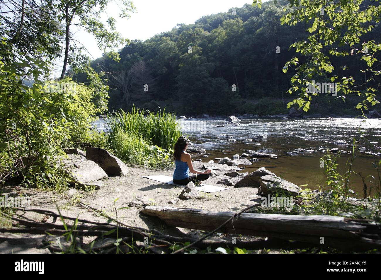 Woman doing yoga on side of river Stock Photo