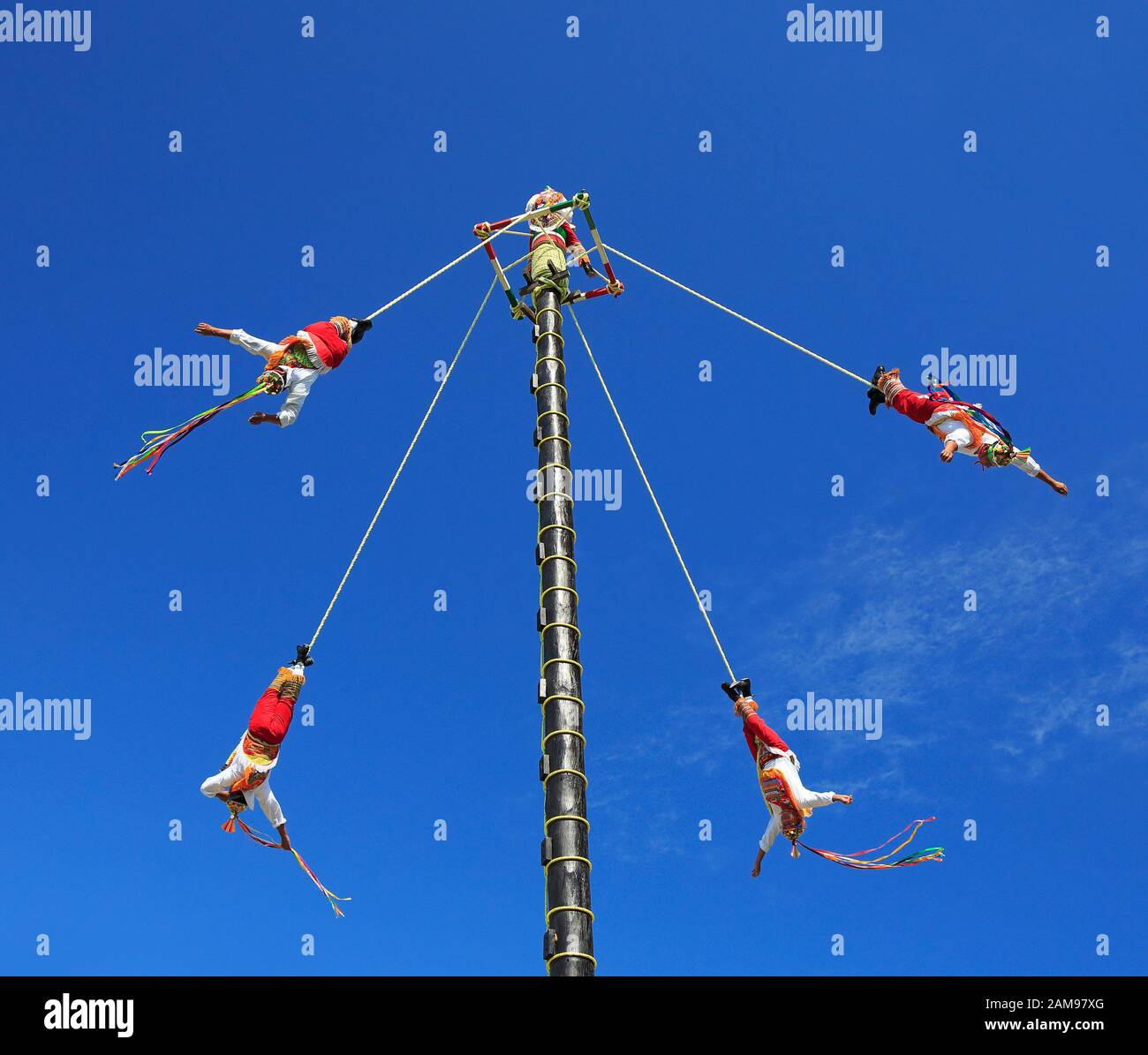 :The Voladores, or flyers performance. They climb up a very high pole their waist to ropes wound around the pole and then jump off, flying gracefully Stock Photo