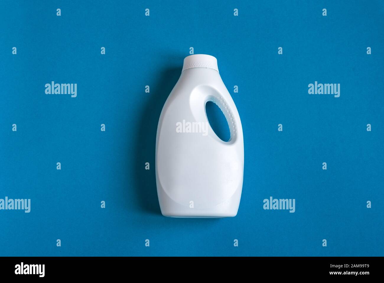 White plastic bottle of cleaning product, household chemicals or liquid laundry detergent on classic blue background, flat lay, top view, copy space. Stock Photo