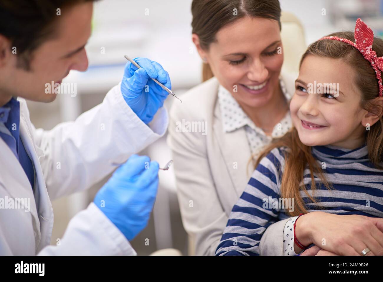 Caring mother encouraging her daughter for a dental exam, healthy teeth concept Stock Photo