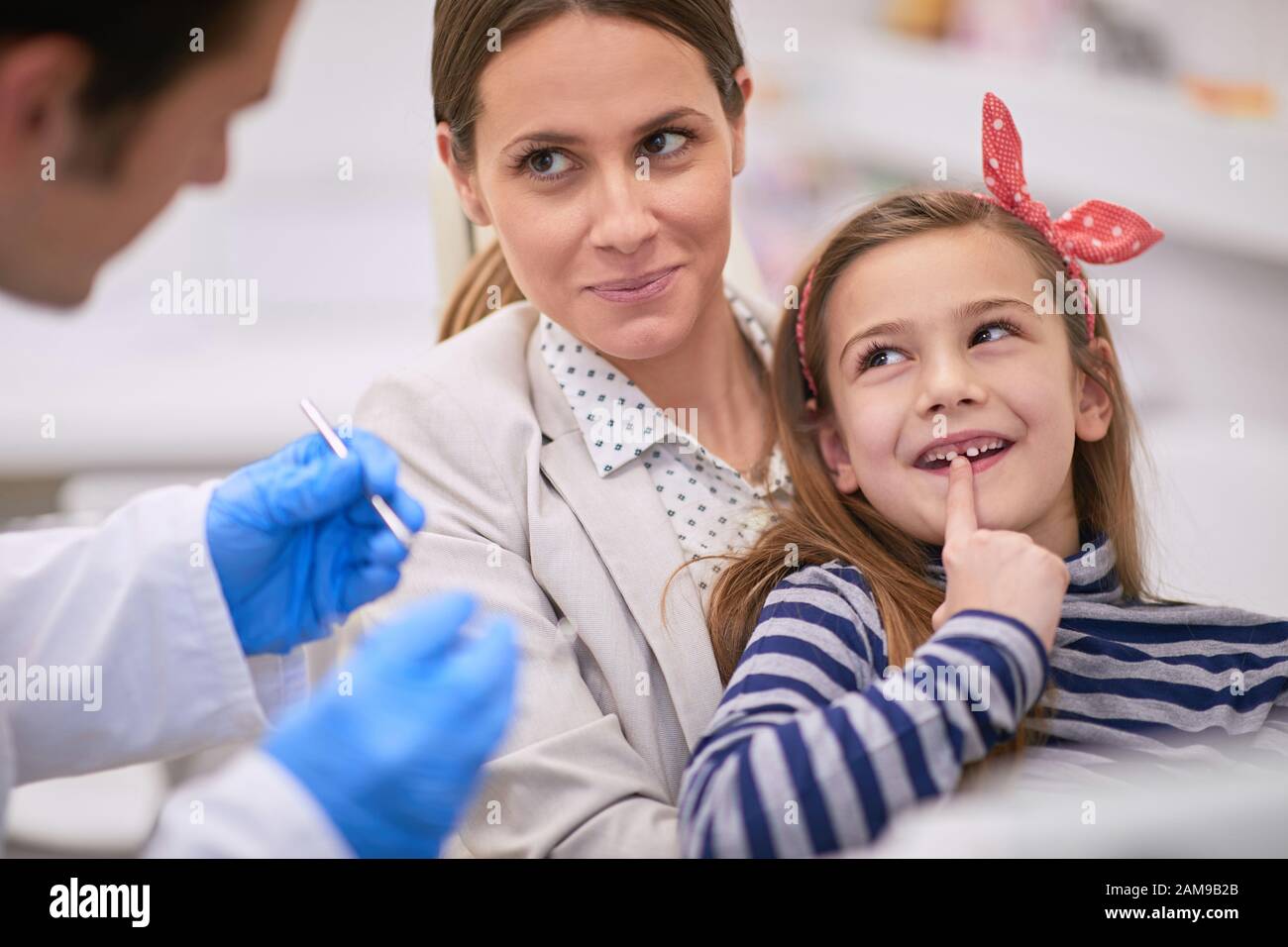Mom and dentist trying to convince sweet little girl to do a dental exam, dentist patient concept Stock Photo