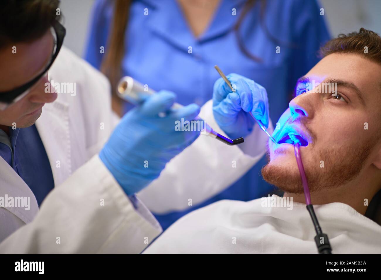 Dentist using dental LED curing light for polymerization of composite