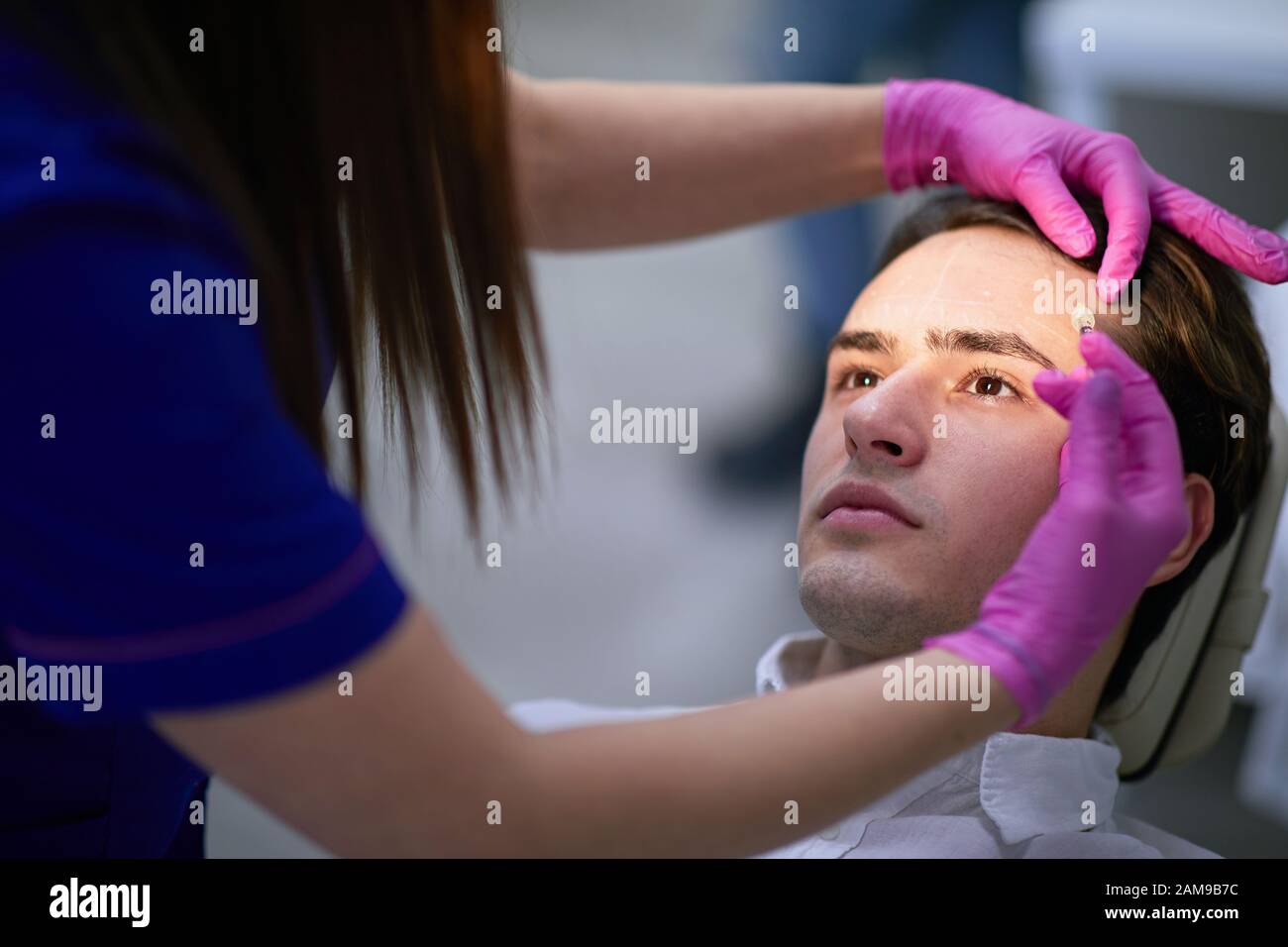 Nurse inserting anti aging substance beneath the forehead skin of a man Stock Photo