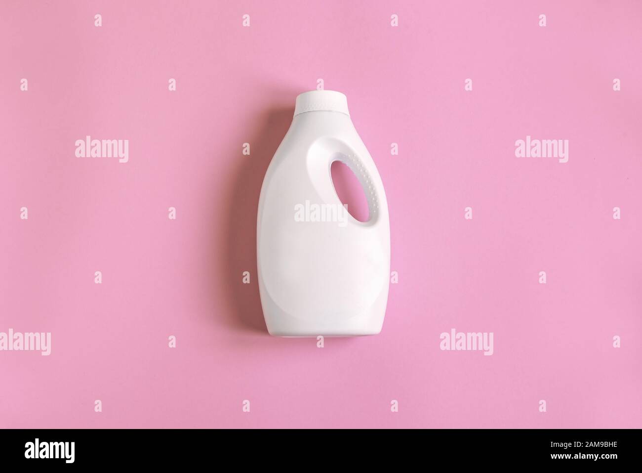 White plastic bottle of cleaning product, household chemicals or liquid laundry detergent on pink pastel background, flat lay, top view, copy space. Stock Photo