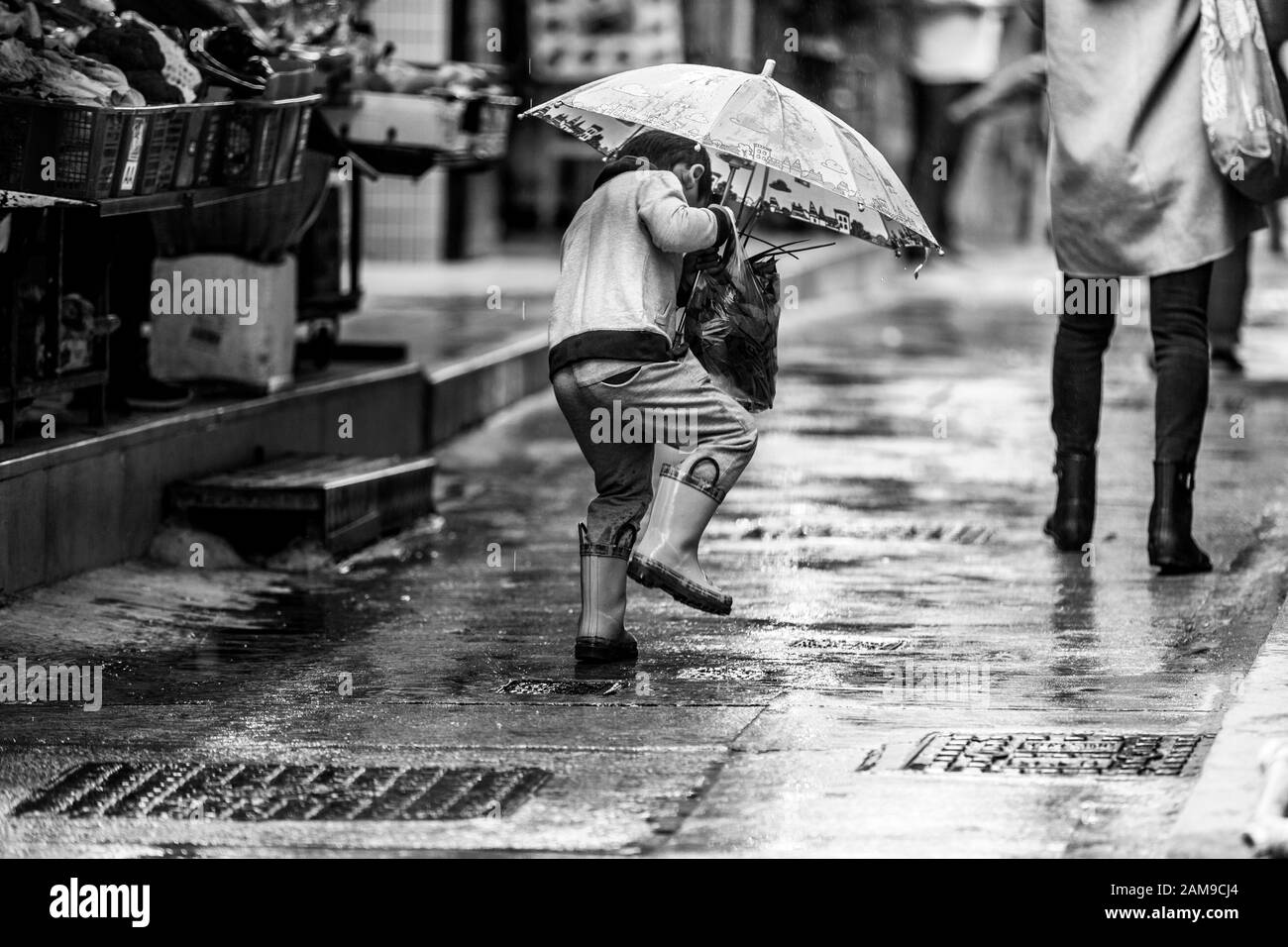 Boy with umbrella playing in the rain in Lamm Island, Hong Kong. Stock Photo