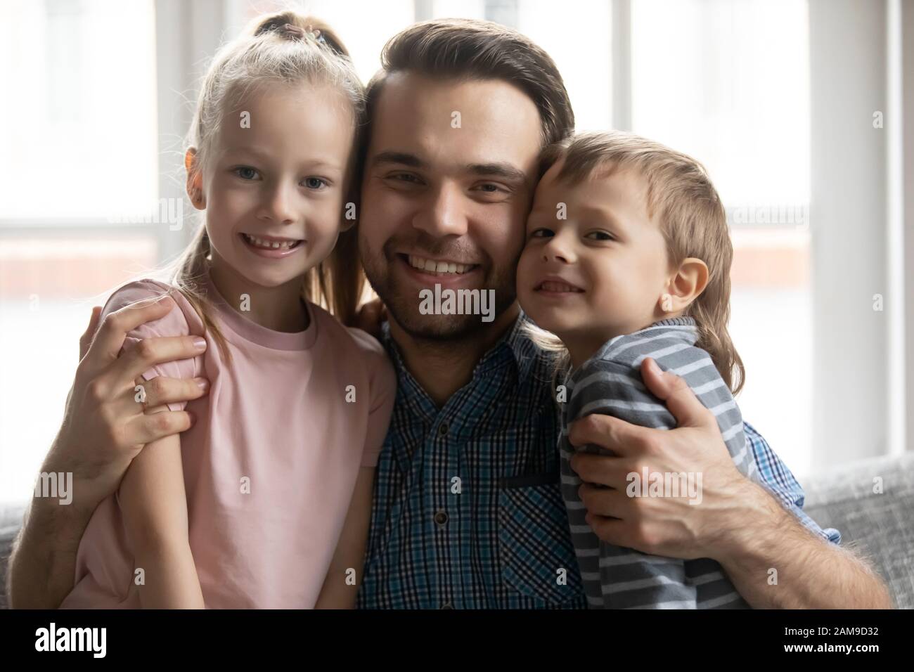 Portrait of smiling father hug cuddle little children Stock Photo