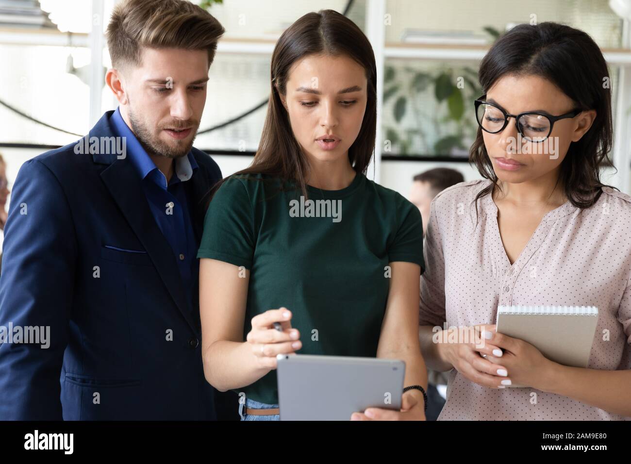 Group of millennial multiethnic workers working together using tablet app Stock Photo