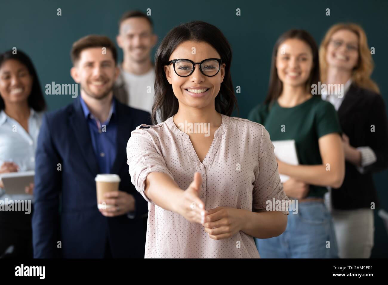 Mixed race woman sales manager stretch out hand greeting client Stock Photo