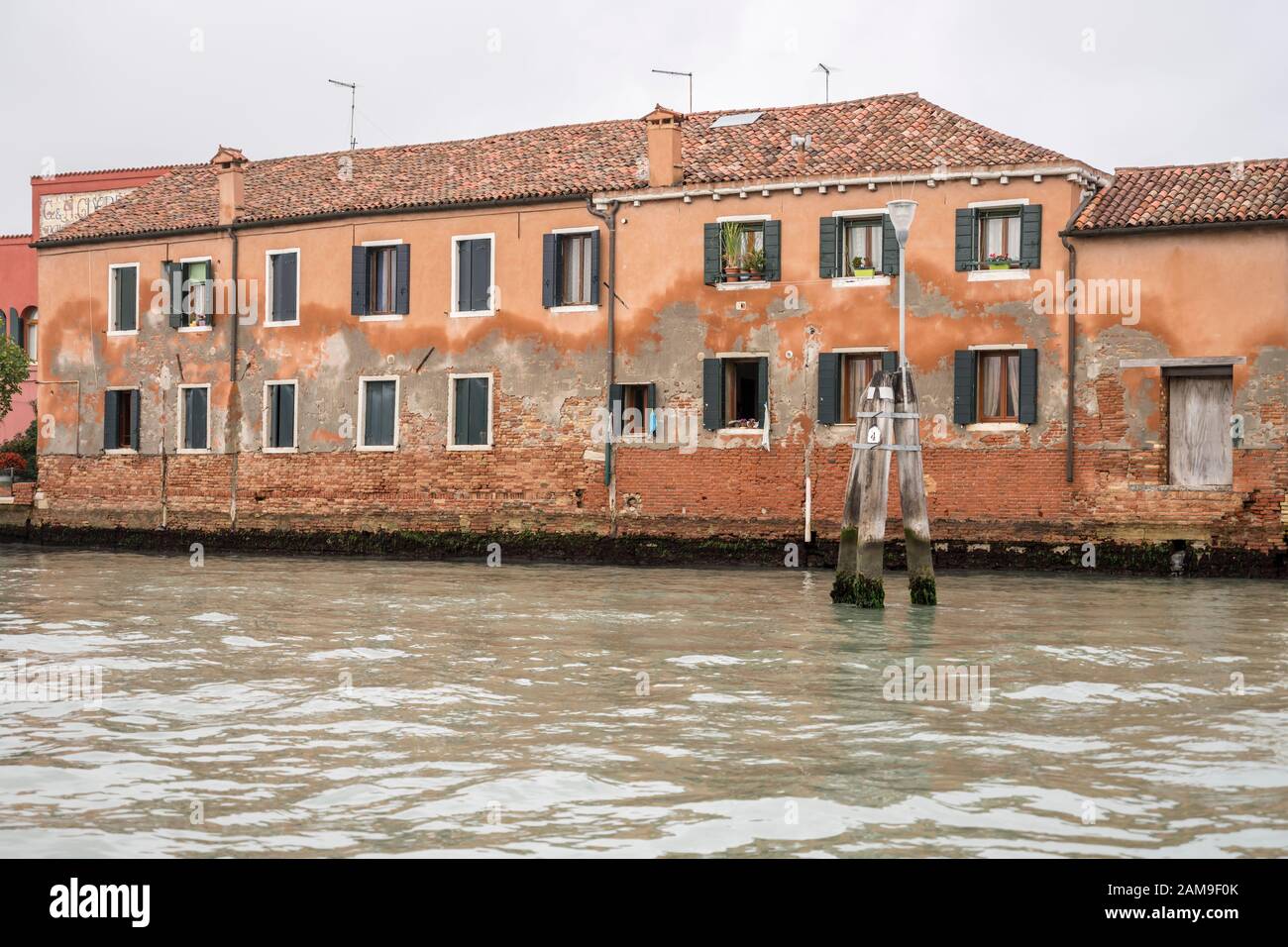 rising damp effects on plaster facade of traditional houses on canal, shot in bright fall light at Murano, Venice, Veneto, Italy Stock Photo