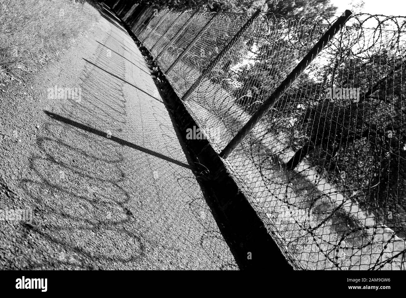 The black and white detail of the fence with a lot of the barbed wire ...