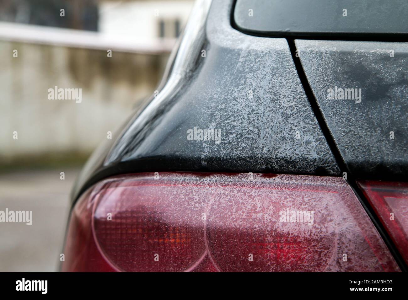 The detail of tail lights of a car during the winter season, dirty with maps from the salt or brine used against snow and ice on the roads. Stock Photo