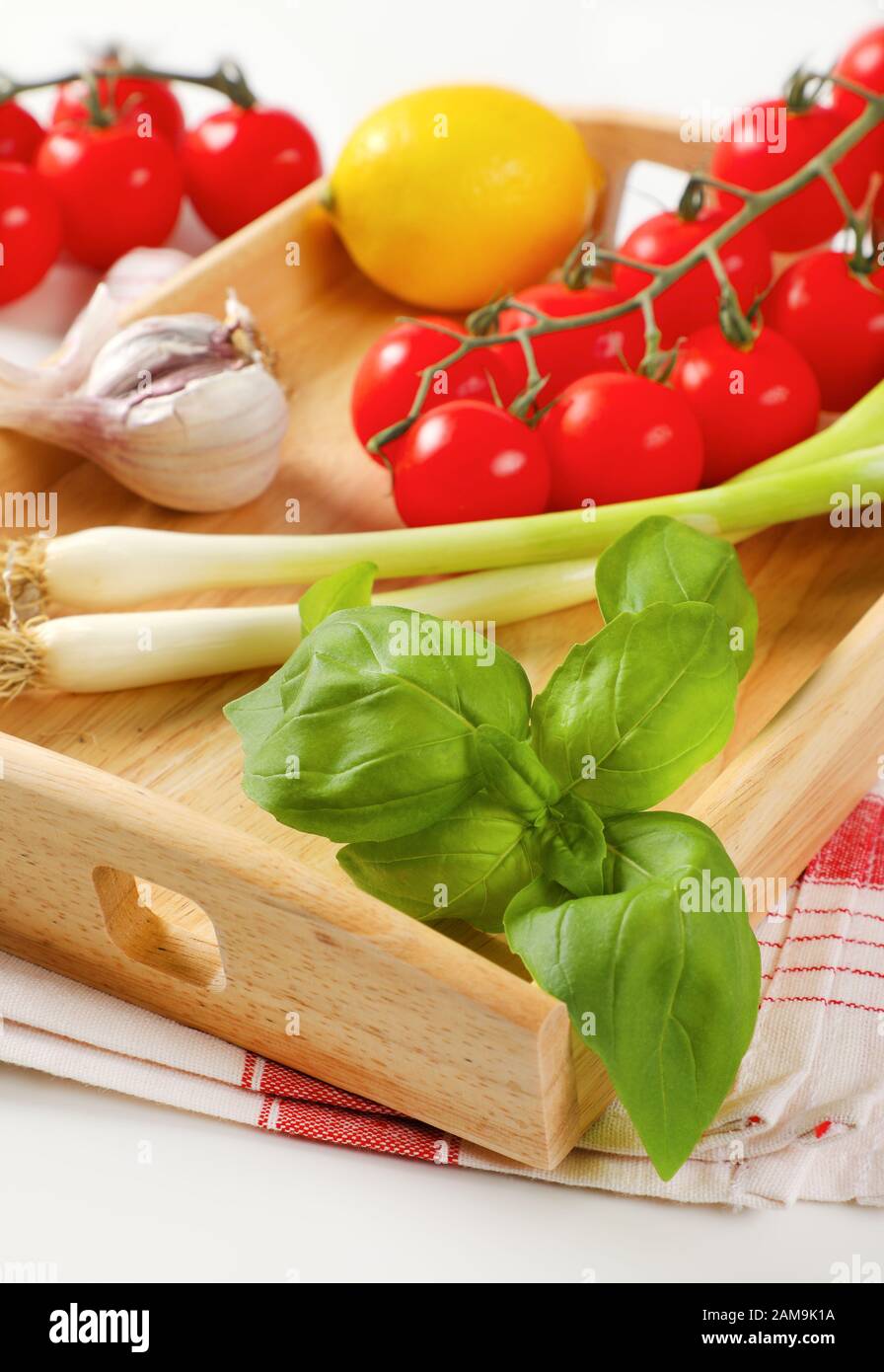 Fresh vegetables and lemon on wooden serving tray Stock Photo