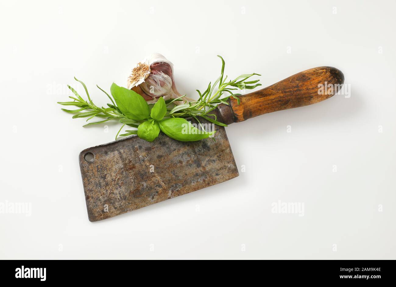 Old rusty meat cleaver knife with fresh basil and rosemary Stock Photo
