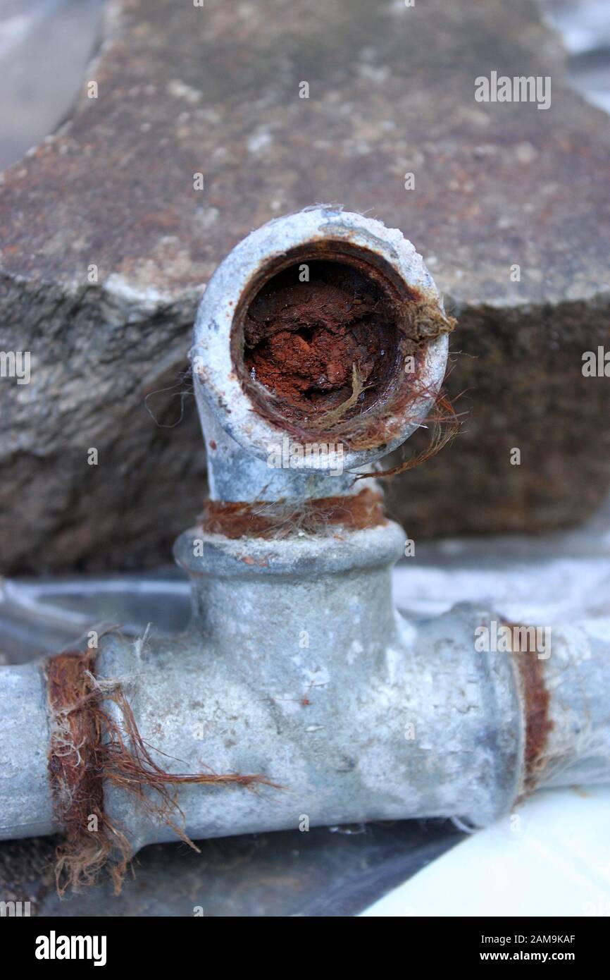 The detail of the old water pipe ingrown with rust. The pipe is full of it and the flow is limited. Needs reconctruction. Stock Photo