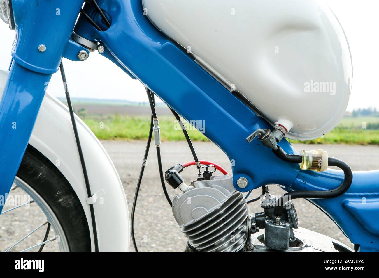 The detail of the old light motorcycle or moped with part of the engine, fuel tank and fuel lead. Stock Photo