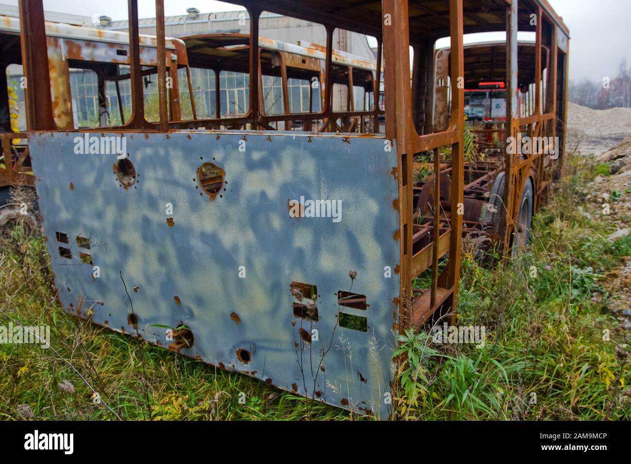 The wrecks of the buses standing on the vehicle cemetery. Waiting to be scrapped. Only rusty constructions sometimes remain. Stock Photo