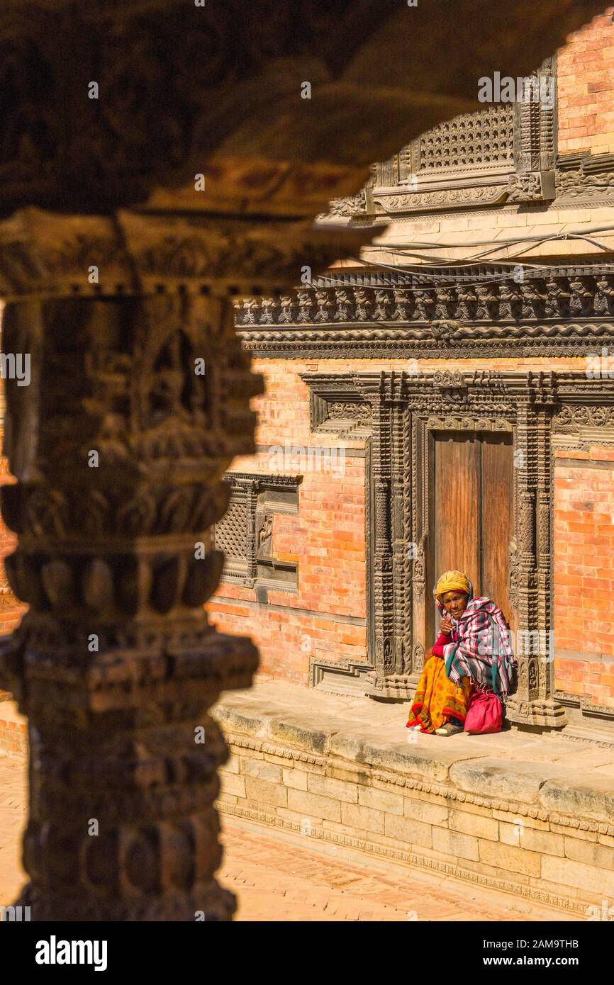 Elderly Nepalese woman on the steps of a temple in Bhaktapur, Nepal Stock Photo