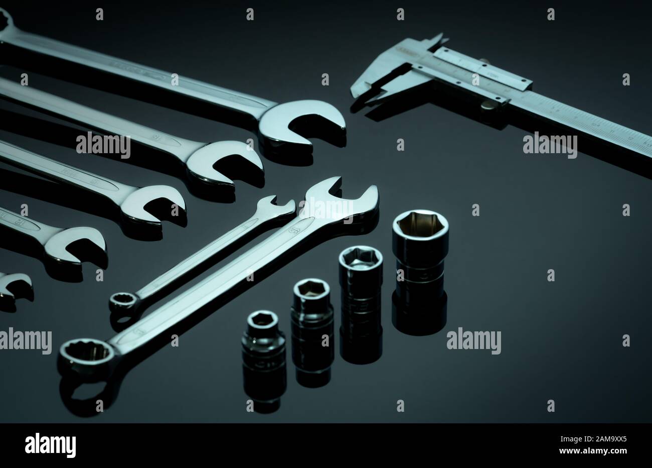 Set of chrome wrenches or spanners, hexagon socket, and vernier caliper on dark table in workshop. Chrome vanadium spanner wrench. Silver wrenches. Stock Photo