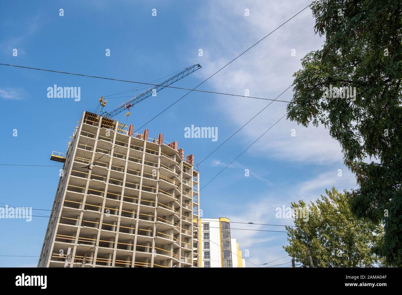 Concrete frame of tall apartment building under construction and tower ...