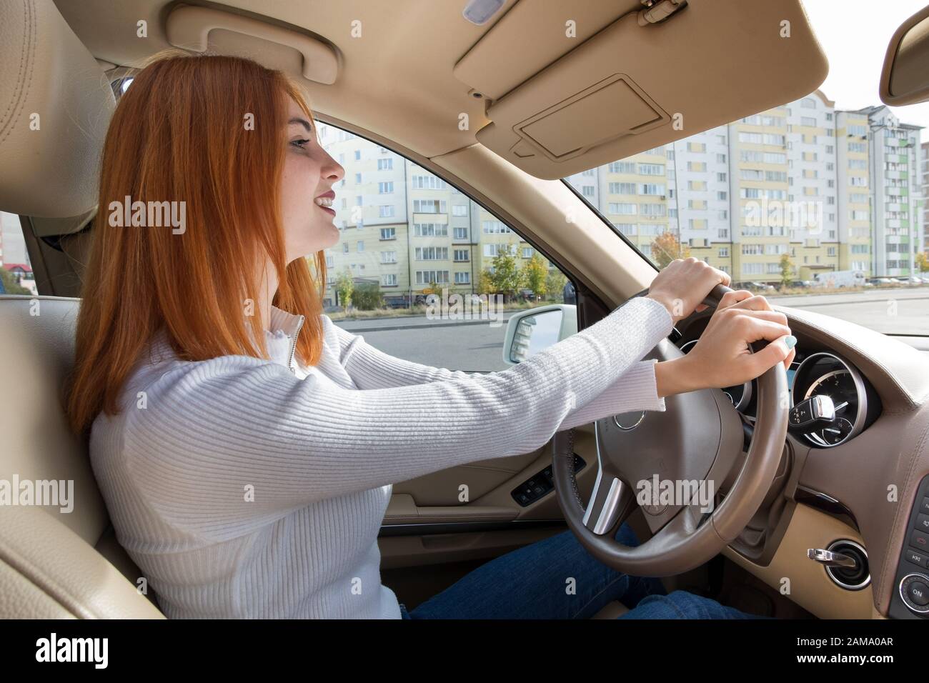 Young redhead woman driver behind a wheel driving a car smiling happily  Stock Photo - Alamy