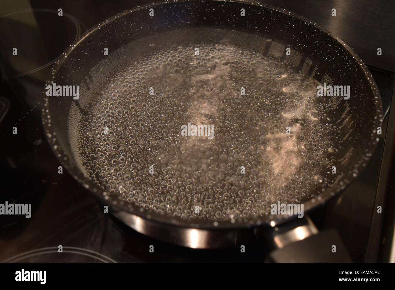 Bubbles in water in a new pan on cooker hob heating up Stock Photo Alamy