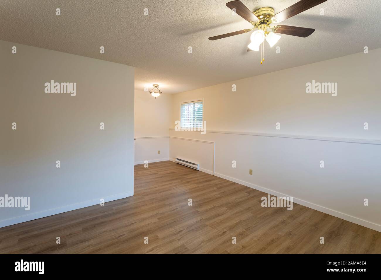 Interior of empty renovated apartment condo rental unit with white walls and new hard wood vinyl laminate flooring. Stock Photo