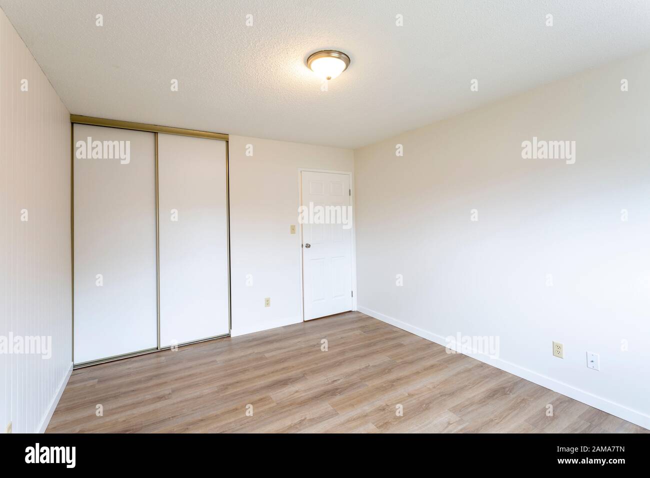 Interior of empty renovated apartment condo rental unit with white walls and new hard wood vinyl laminate flooring. Stock Photo