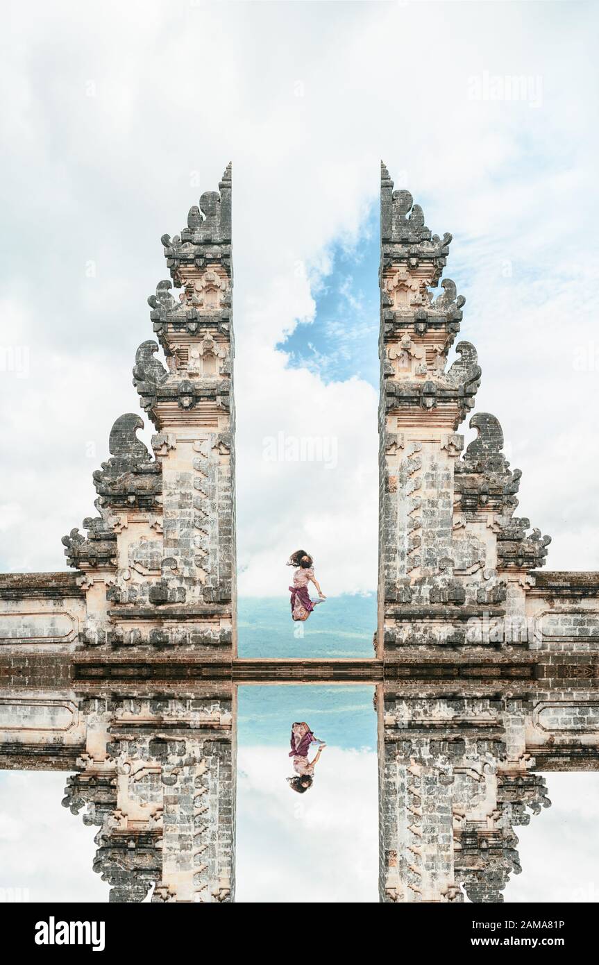 A girl is jumping in front of the Gate of Heaven with its reflection in the water. Stock Photo