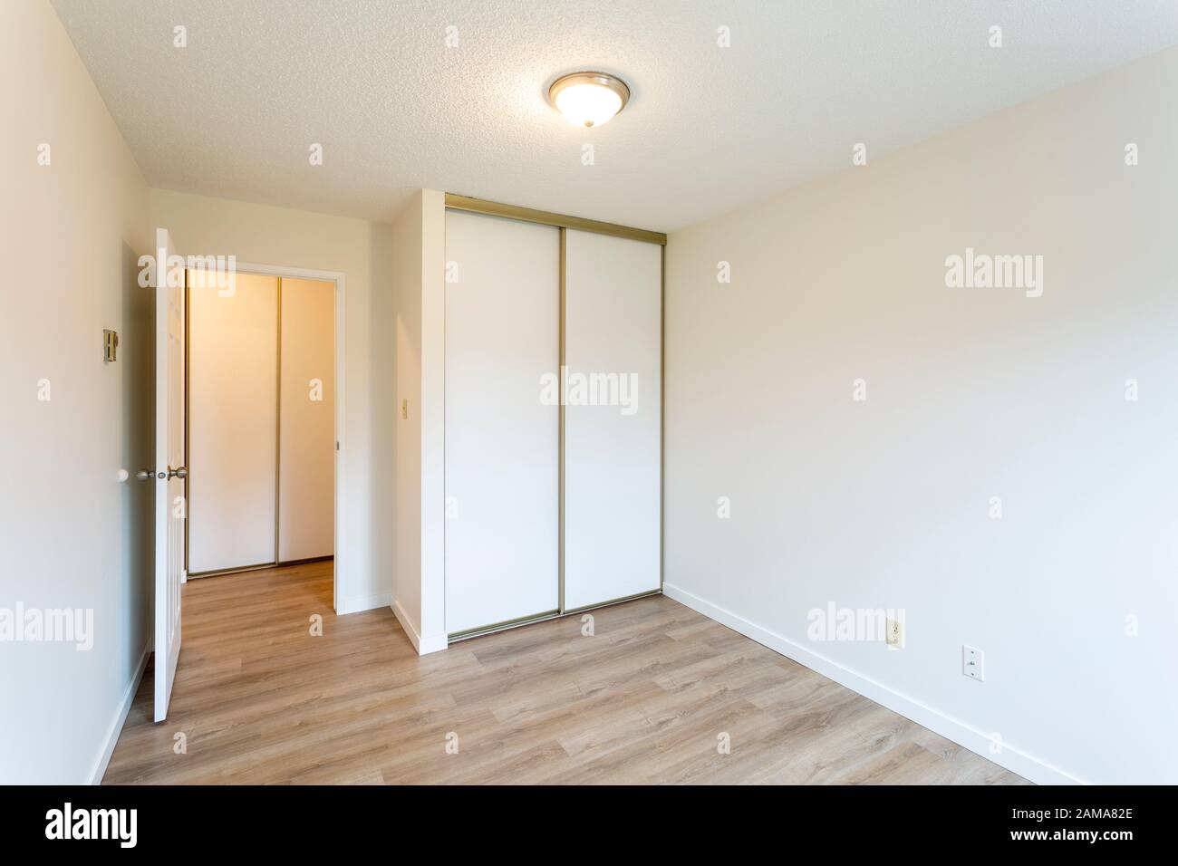 Interior of empty renovated apartment condo rental unit with white walls and new hard wood vinyl laminate flooring. Stock Photo