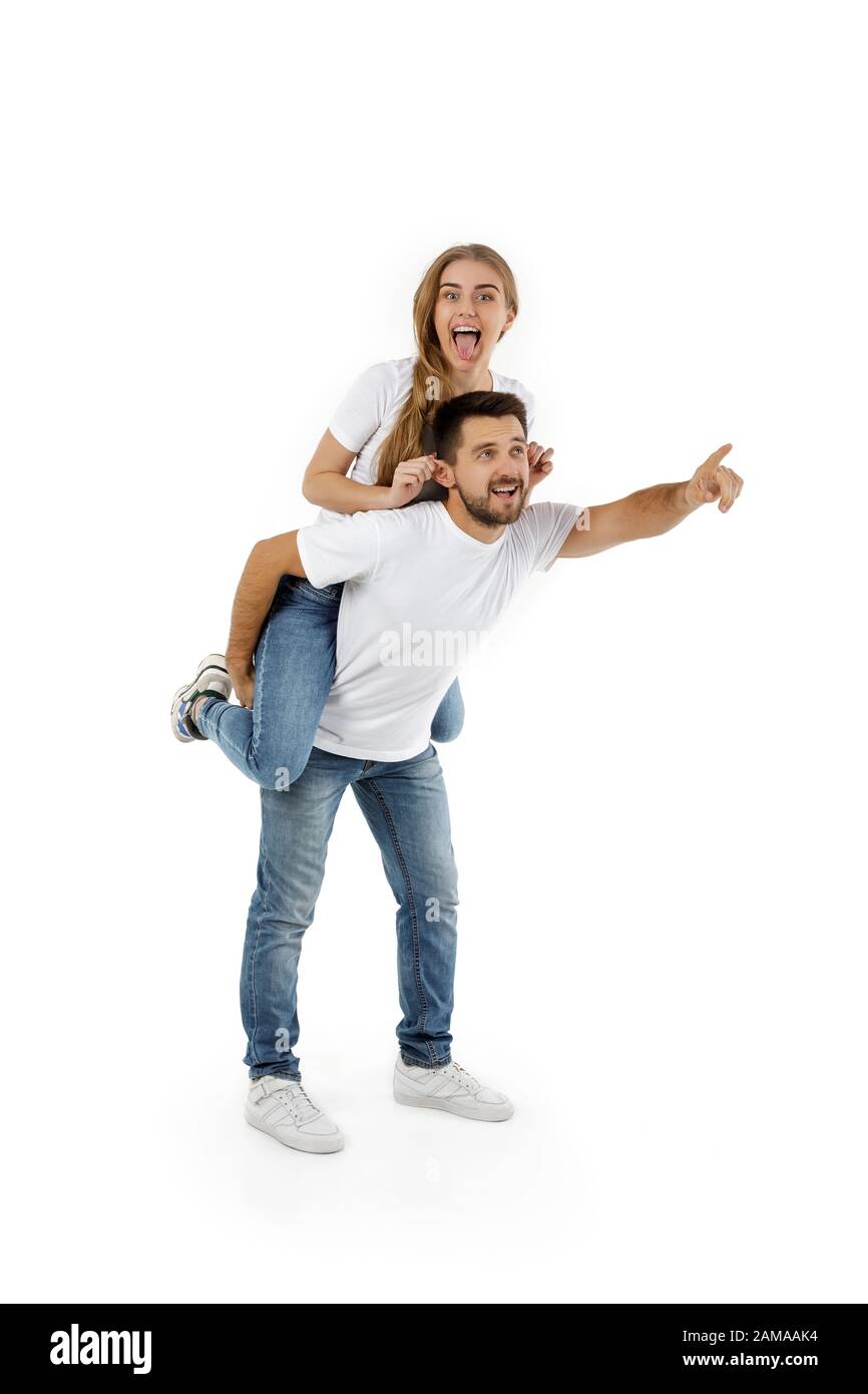 man carrying young woman on his back. boyfriend giving piggyback to girlfriend on white background Stock Photo