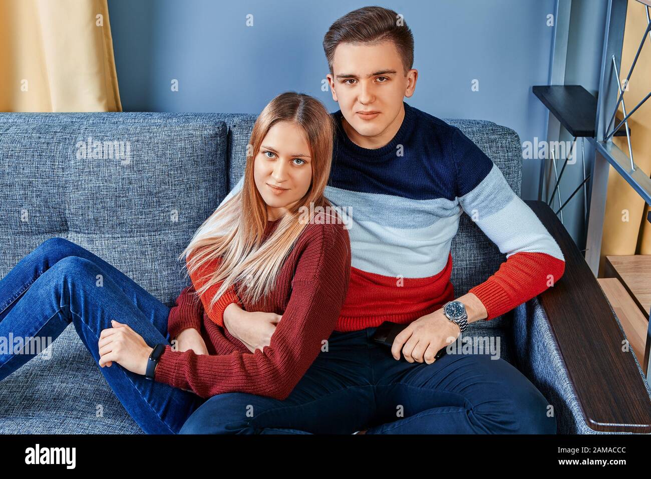 Lovers are sitting on a sofa in a college dorm room. Romantic date of a young man and woman in a