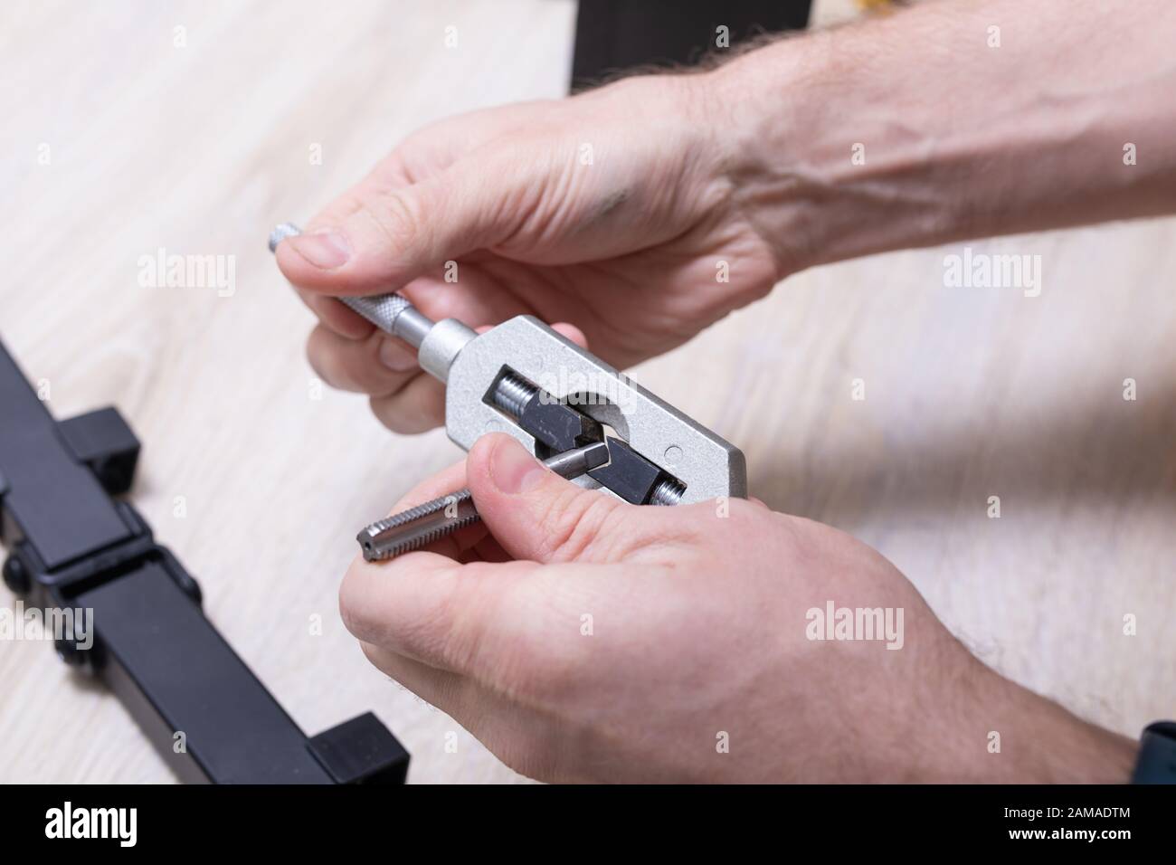 Man use mechanical hand tool, device for making threads in a screw. Stock Photo