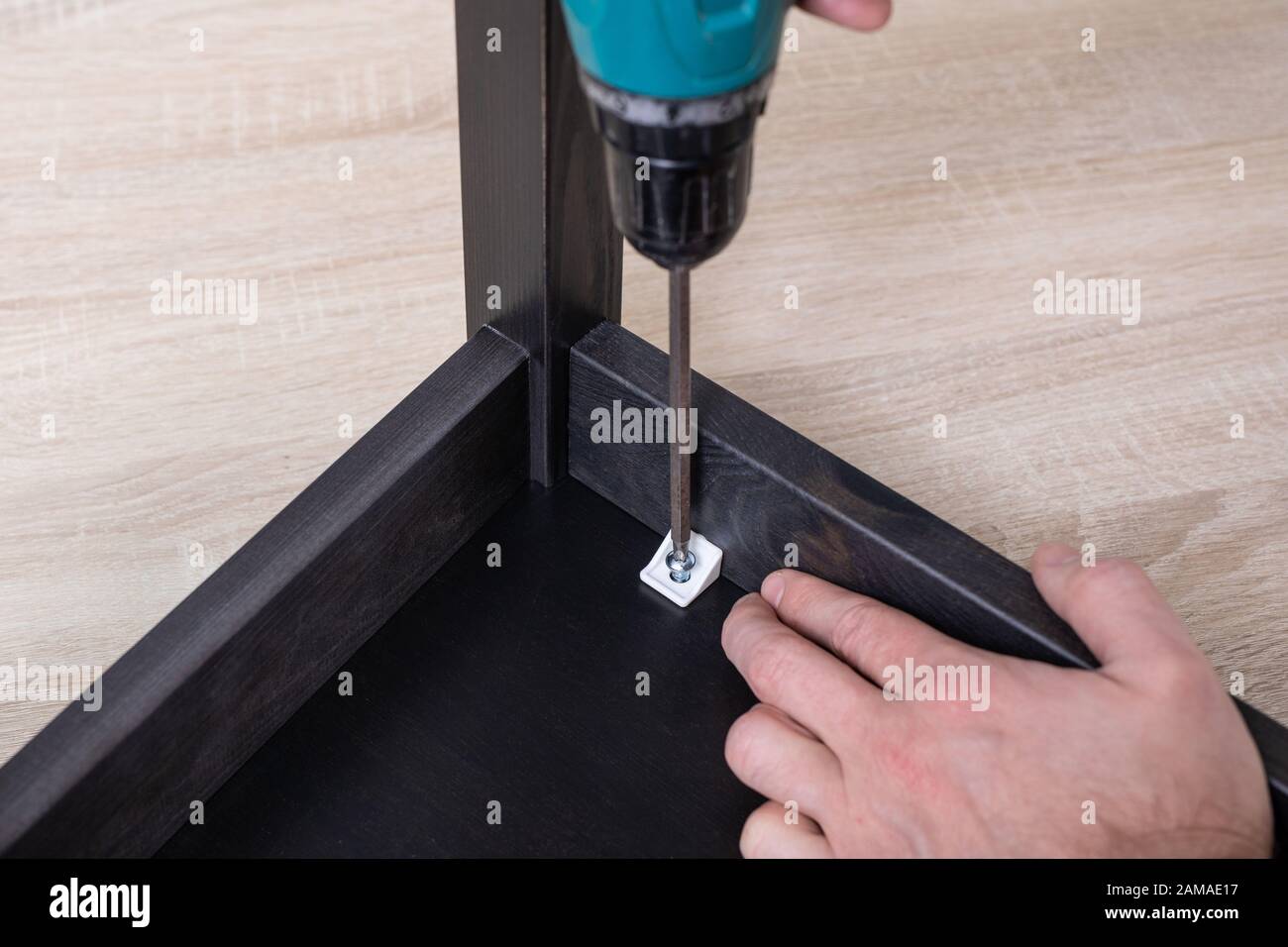 Power electric screwdriver. Carpenter working with hand tool on work bench. Closeup view. Stock Photo